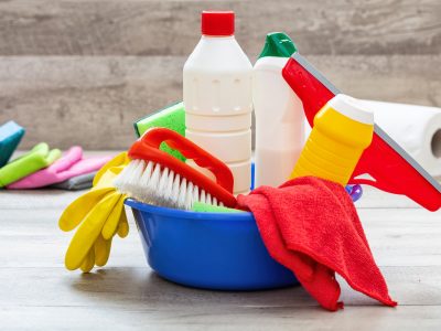 Cleaning supplies in a blue bowl, wooden floor background.